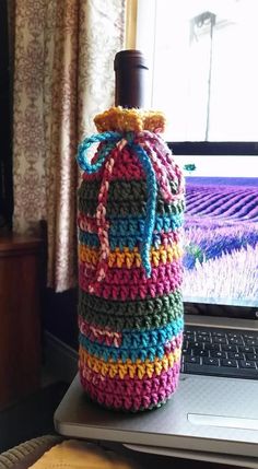 a crocheted bag sitting on top of a laptop computer next to a window