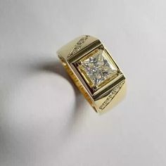 a yellow gold ring with a princess cut diamond set in the center, on a white background