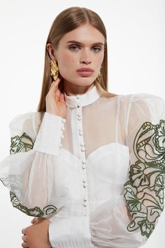 a woman wearing a white blouse and gold earrings