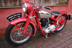 a red motorcycle parked on top of a brick road next to a building with a sign