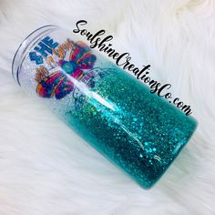 a blue and green glittered cup sitting on top of a white fur covered floor