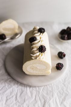 a cake with white frosting and blackberries on it is sitting on a plate