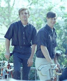 two men standing next to each other with bicycles