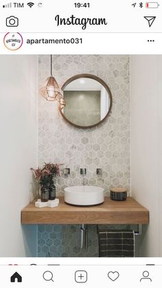 a bathroom sink sitting under a mirror on top of a wooden counter next to a plant