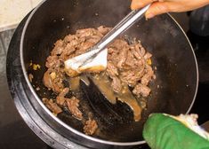 someone is cooking food in a large pan on the stove with a spatula to stir it