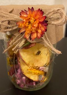 an orange flower in a glass jar with twine and burlock tied around it