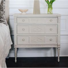 a white dresser sitting next to a bed in a bedroom