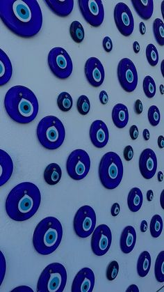 many blue circles are arranged on a white wall and one has an eyeball in the center