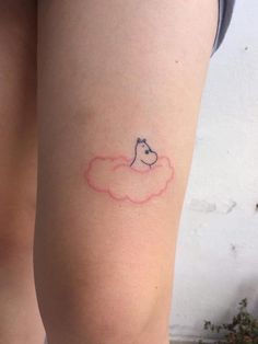 a woman's thigh with a small tattoo of a dog on top of a cloud