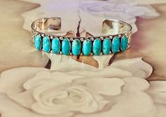 "Genuine Kingman Turquoise Bracelet.  She is so pretty with 10 beautiful stones with earthtone matrix in each stone.  Beautiful silversmith stamping on the sides. * Kingman Turquoise * Handcrafted and Hallmarked 925 Sterling silver * 5.5\" from end to end with a 1.5\" gap * Fits sizes 6.5\" to 8\" * FREE SHIPPING * Not Native Made" Luxury Adjustable Kingman Turquoise Bracelets, Luxury Kingman Turquoise Gemstone Bracelets, Luxury Handmade Kingman Turquoise Bracelets, Luxury Adjustable Kingman Turquoise Bracelet, Luxury Kingman Turquoise Gemstone Bracelet, Luxury Kingman Turquoise Multi-stone Jewelry, Luxury Kingman Turquoise Bangle Bracelet, Luxury Multi-stone Kingman Turquoise Jewelry, Turquoise Hoop Earrings