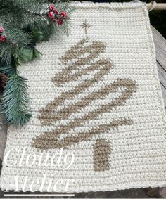 a crocheted christmas tree rug on a wooden table with pine cones and evergreen branches