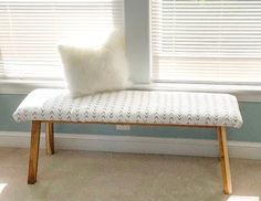 a white bench sitting in front of a window with a pillow on top of it