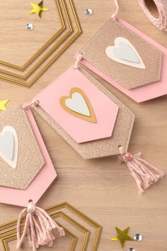 some pink and gold tags with hearts on them sitting on top of a wooden table