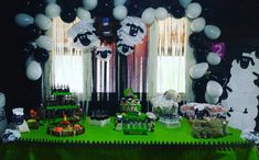 a green table topped with lots of black and white balloons in the shape of sheep