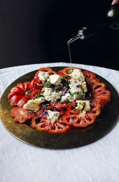 a person is drizzling cheese on top of tomatoes and other food items