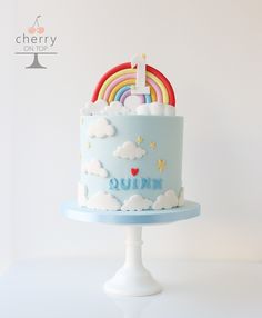 there is a blue cake with rainbows and clouds on the top that says quirn