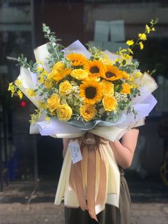 a woman holding a bouquet of yellow flowers