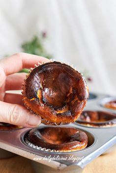 a person holding up a pastry in a muffin tin