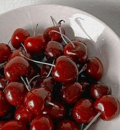 a white bowl filled with cherries on top of a table