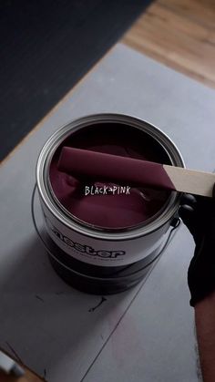 a person is holding a paint brush in their hand and painting the inside of a can