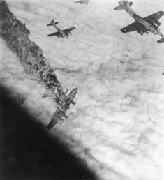 four airplanes flying in the sky above some clouds and grass, with another plane hovering over them