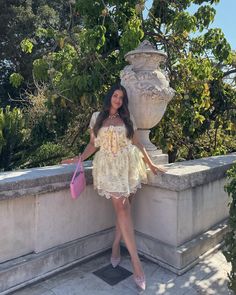 a woman in a dress leaning against a stone wall