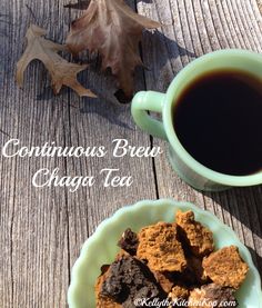 a cup of coffee sitting next to a plate of cookies on a wooden table with leaves