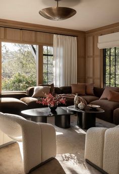 a living room filled with lots of furniture next to a large window covered in curtains