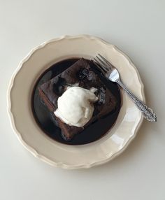 a white plate topped with brownies and ice cream next to a knife and fork