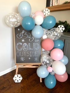 a baby's cold outside sign surrounded by balloons and snowflakes