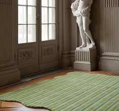 there is a statue in the corner of this room with a rug on the floor