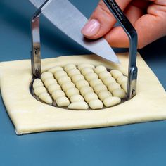 a person using a pair of scissors to cut small pieces of dough on a cutting board