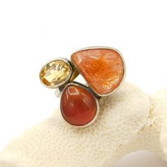 This big vintage sterling ring has a really nice sturdy, quality adjustable band. Three stones in open backed settings are different sizes, shapes and colors which make me think of pop art. The light kind of peachy brownish color has some almost sparkling flecks (very subtle) and the darker stone could be carnelian but I do not know and the yellow faceted stone I believe is a cubic zirconium. Currently about a size 9 but it is adjustable and could easily be size 9 1/2 and go down to size 7 I wou Unique Orange Cabochon Ring, Triple Hoop Earrings, Napier Jewelry, Art Ring, Big Hoop Earrings, Sterling Jewelry, Hinged Bangle, Multi Stone Ring, May 21