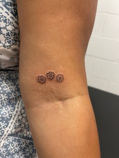 a woman's arm with three small flowers on the back of her left arm