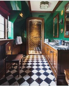 a bathroom with green walls and black and white checkerboard flooring on the tile