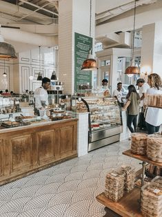 people are standing in line at the counter of a bakery with lots of food on it