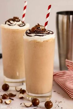 two glasses filled with chocolate milkshakes on top of a table