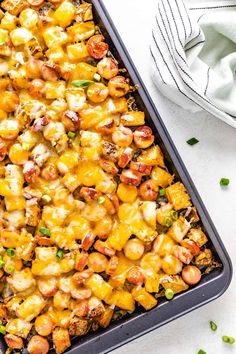 a casserole dish with chicken and vegetables in it on a white surface next to a fork