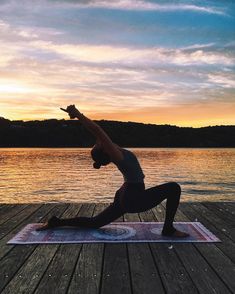 a woman doing yoga on a dock at sunset