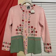 a pink and green sweater with flowers on the front is sitting on a mannequin's head