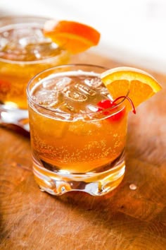 two glasses filled with orange juice on top of a wooden table