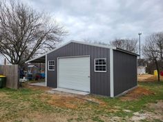 a garage with a shed attached to it in the middle of a yard next to a fence