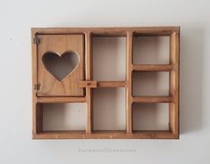 a wooden box with several compartments and a heart cut out in the middle, on a white wall