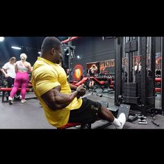 a man sitting on top of a bench in a gym next to other people working out