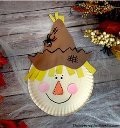 a paper plate with a scarecrow face on it and fall leaves around the edges