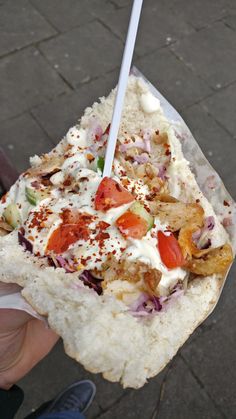 a person holding a piece of bread with toppings on it and a toothpick in their hand