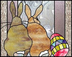 two rabbits sitting next to each other in front of a stained glass window with an easter egg