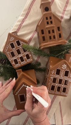 a woman is decorating some gingerbread houses