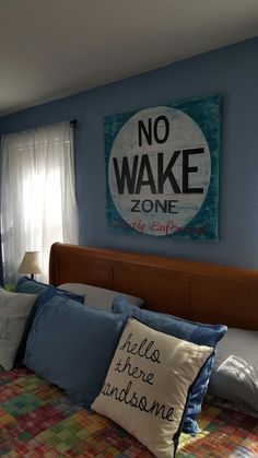 there is a bed with pillows on it and a no wake sign above the headboard