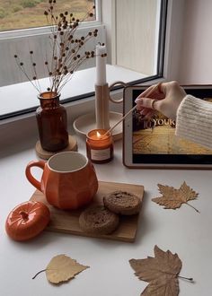 there is a tablet on the table next to some autumn leaves and coffee mugs